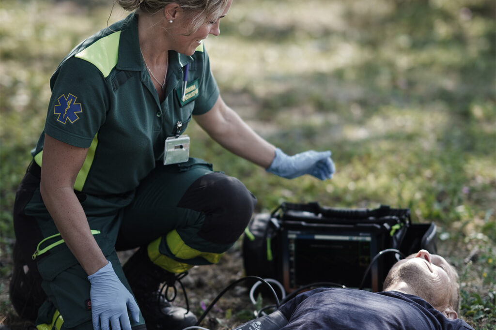 MobiMed vid patient utomhus på marken där olycka skett med ambulanspersonal på plats som mäter vitala värden