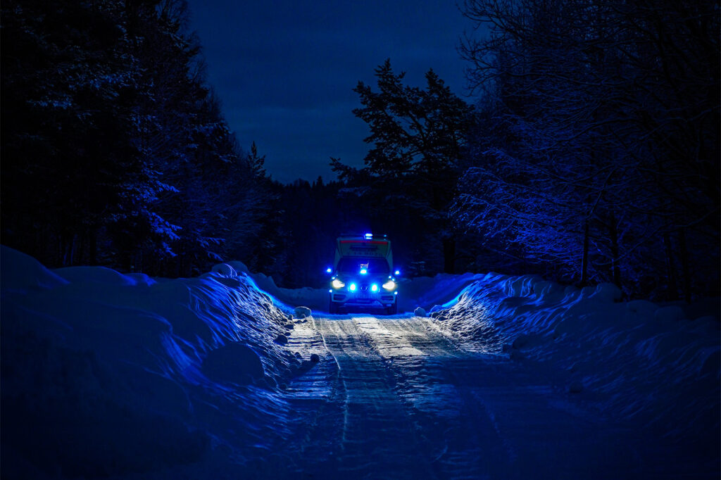 Ambulance in the forrest with blue lights on heading towards an emergency