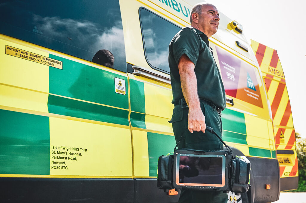 Paramedic standing next to ambulance in the sun on their way to connect a patient to MobiMed electronic patient journal