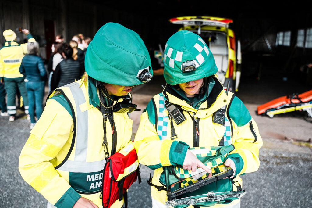 Paramedics is holding a MobiMed monitor in their hands looking at data