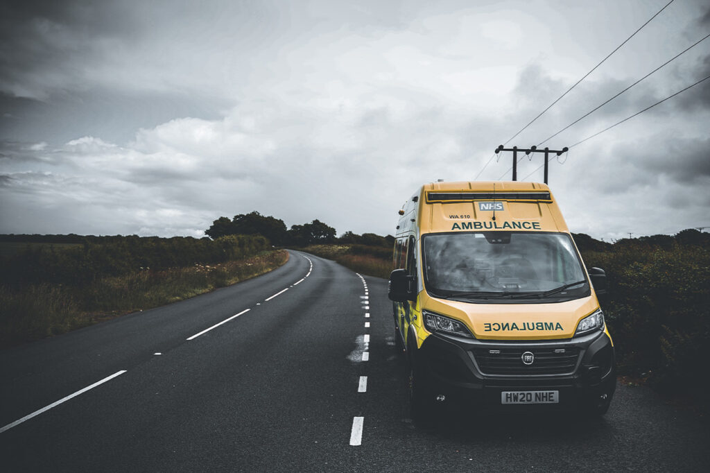 ambulance parked on road in Isle of Wight with paramedics rushing to scen